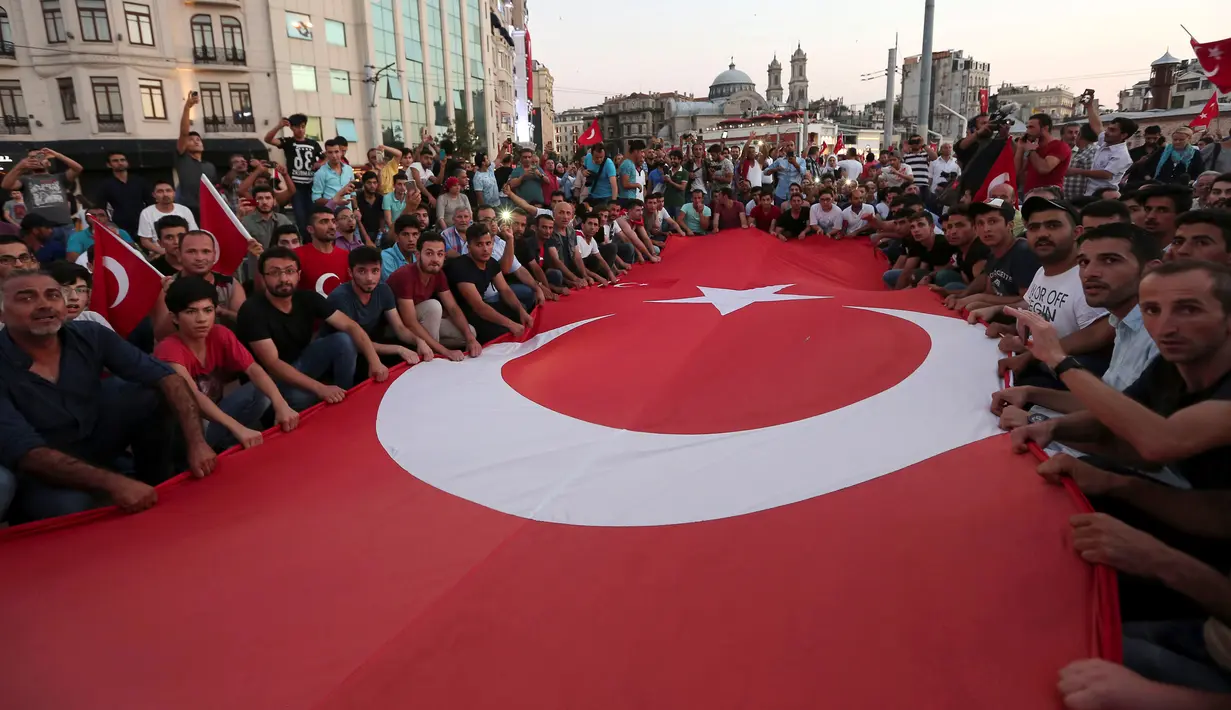 Bendera nasional Turki berukuran besar dibentangkan pendukung Presiden Turki, Tayyip Erdogan di Taksim Square, pusat kota Istanbul, Sabtu (16/7). Ratusan warga turun ke jalan untuk merayakan kegagalan kudeta militer di Turki. (REUTERS/Huseyin Aldemir)