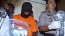 Petugas kepolisian mengawal tersangka kasus pembunuhan, Putu Astawa di kantor Polisi Bali, Denpasar (18/9). Astawa ditetapkan sebagai pelaku utama pembantaian pasutri Jepang berdasarkan alat bukti yang ditemukan di TKP. (AP Photo/Firdia Lisnawati)