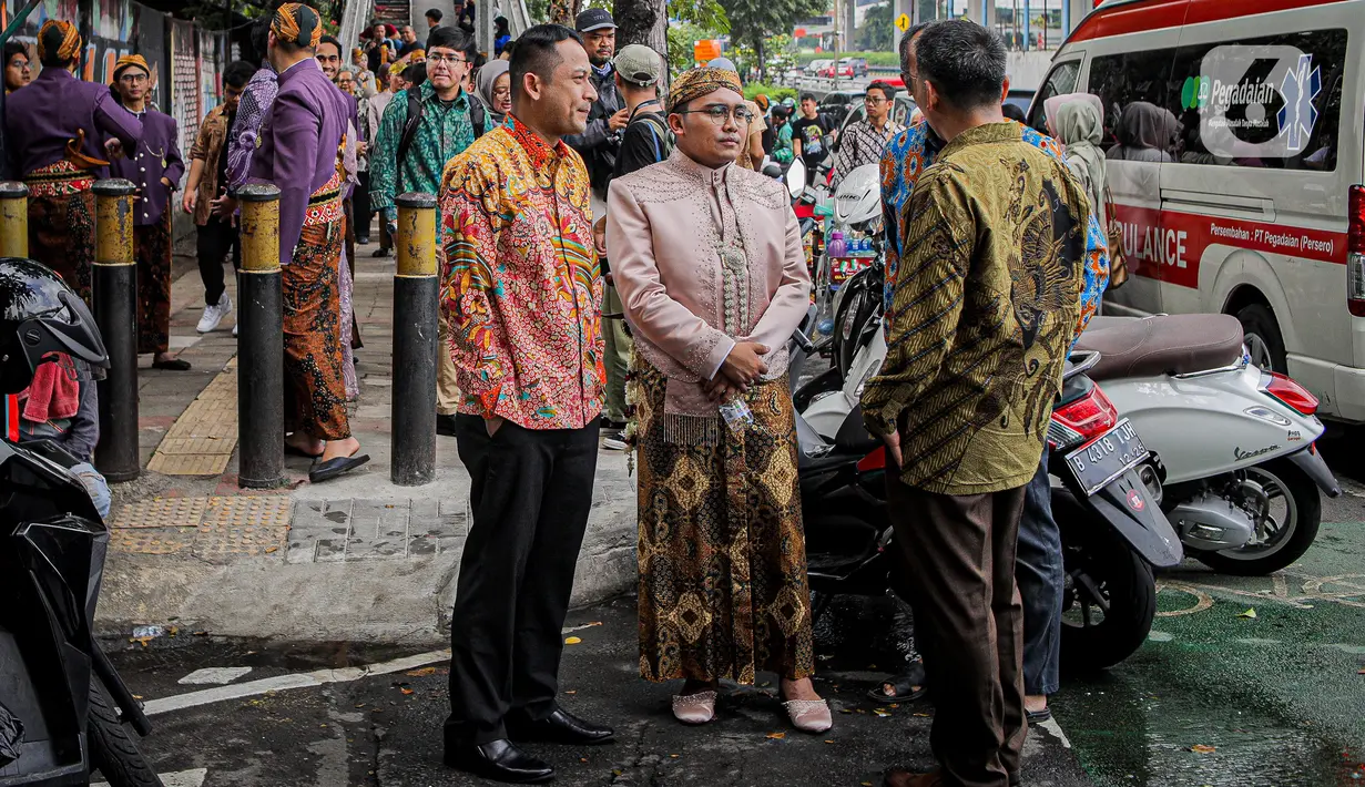 Keluarga pengantin yang menjalani resepsi di lantai 5 gedung K-Link Tower yang terbakar menunggu di trotoar Jl Gatot Subroto, Jakarta, Sabtu (15/7/2023). (Liputan6.com/Faizal Fanani)