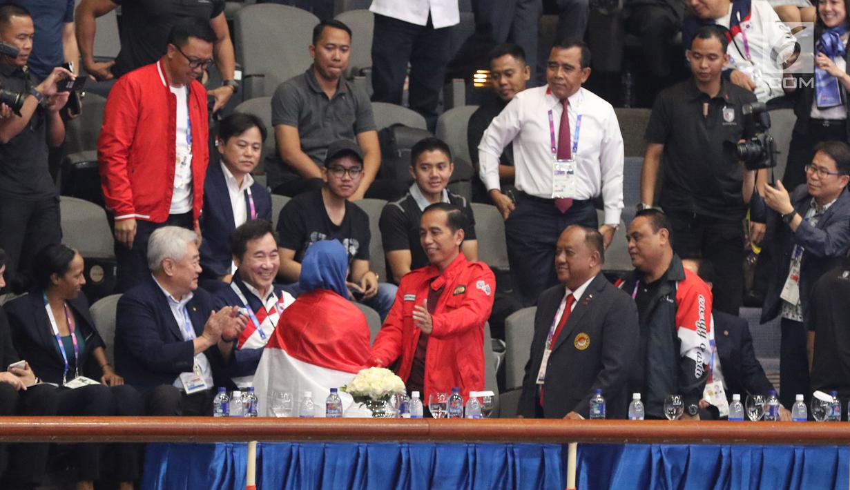 Atlet Taekwondo putri Indonesia, Defia Rosmaniar menyalami Presiden Joko Widodo usai merayakan kemenangan atas Salahshouri Marjan (Iran) pada Final Women Individual Poomsae di JCC, Jakarta, Minggu (19/8). (Liputan6.com/Helmi Fithriansyah)