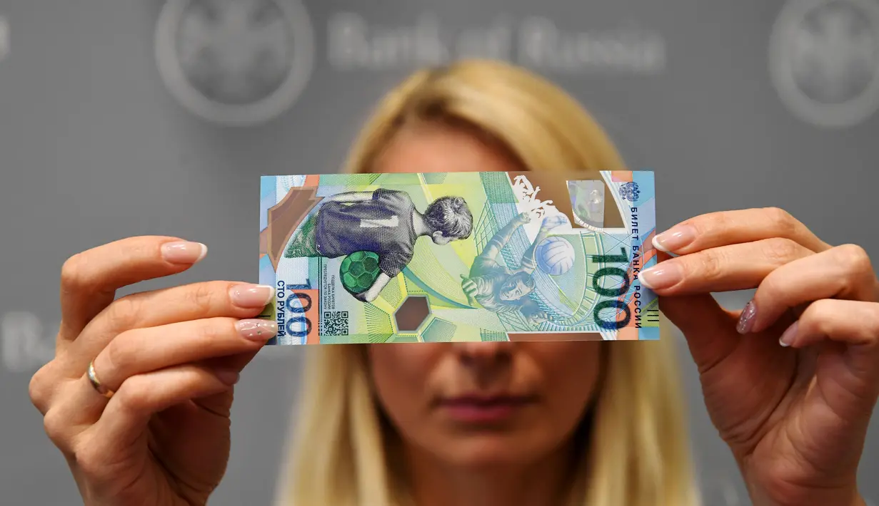 Seorang wanita menunjukkan uang kertas pecahan 100 rubel baru yang dirancang khusus untuk Piala Dunia 2018 di Moskow, Rusia, Selasa (22/5). Sekitar 20 juta uang kertas polimer akan dimasukkan ke dalam sirkulasi. (AFP/Kirill KUDRYAVTSEV)