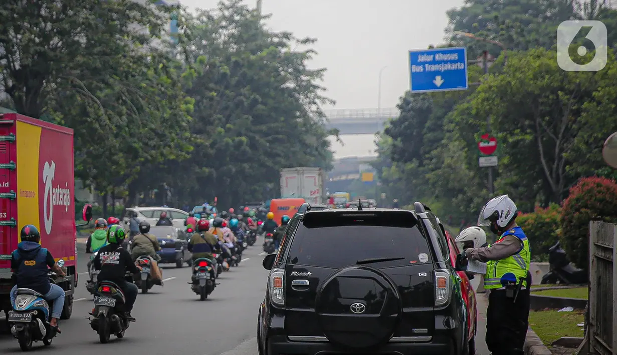 Anggota polisi melakukan penindakan kepada sebuah kendaraan saat ganjil genap di kawasan Jalan D.I Panjaitan, Jakarta, Senin (6/6/2022). Pembatasan mobil dengan sistem pelat nomor ganjil genap di Jakarta diperluas menjadi 25 titik mulai hari ini, Senin, 6 Juni 2022. (Liputan6.com/Faizal Fanani)