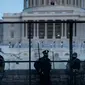 Petugas Kepolisian Capitol berjaga bersama pasukan Garda Nasional di belakang pagar pengendali kerumunan di sekitar Capitol Hill AS di Washington, Kamis (7/1/2021). Peristiwa penyerbuan di gedung Capitol Hill AS dilakukan oleh massa pendukung Donald Trump pada 6 Januari. (Brendan Smialowski/AFP)