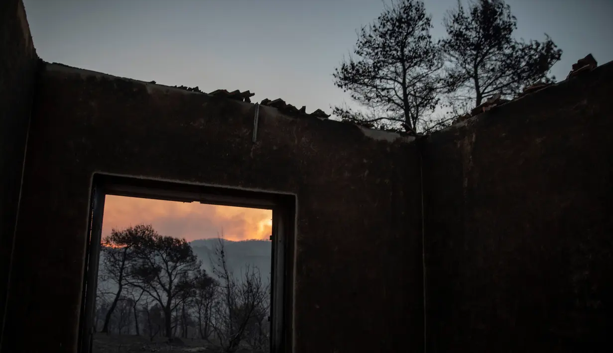 Sebuah rumah terbakar di Desa Galataki, Corinth, Yunani, Kamis (23/7/2020). Pemadam kebakaran dan pesawat yang menjatuhkan air berjuang untuk memedamkan api. (AP Photo/Petros Giannakouris)