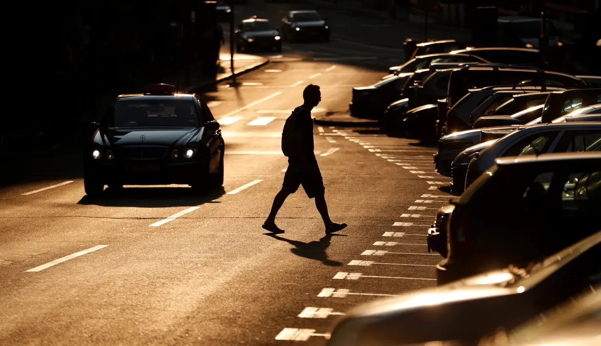 Seorang pria melintasi jalan saat matahari terbenam di Beograd, Serbia, Kamis (2/7/2020). (AP Photo/Darko Vojinovic)