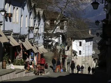 Orang-orang berjalan-jalan di kota Gjirokastra, Albania selatan pada 5 Februari 2021. Pariwisata telah berkembang di kota Gjirokastra, yang diakui sebagai Situs Warisan Dunia UNESCO, tetapi pandemi virus corona menghentikannya secara tiba-tiba. (AP Photo/Hektor Pustina)