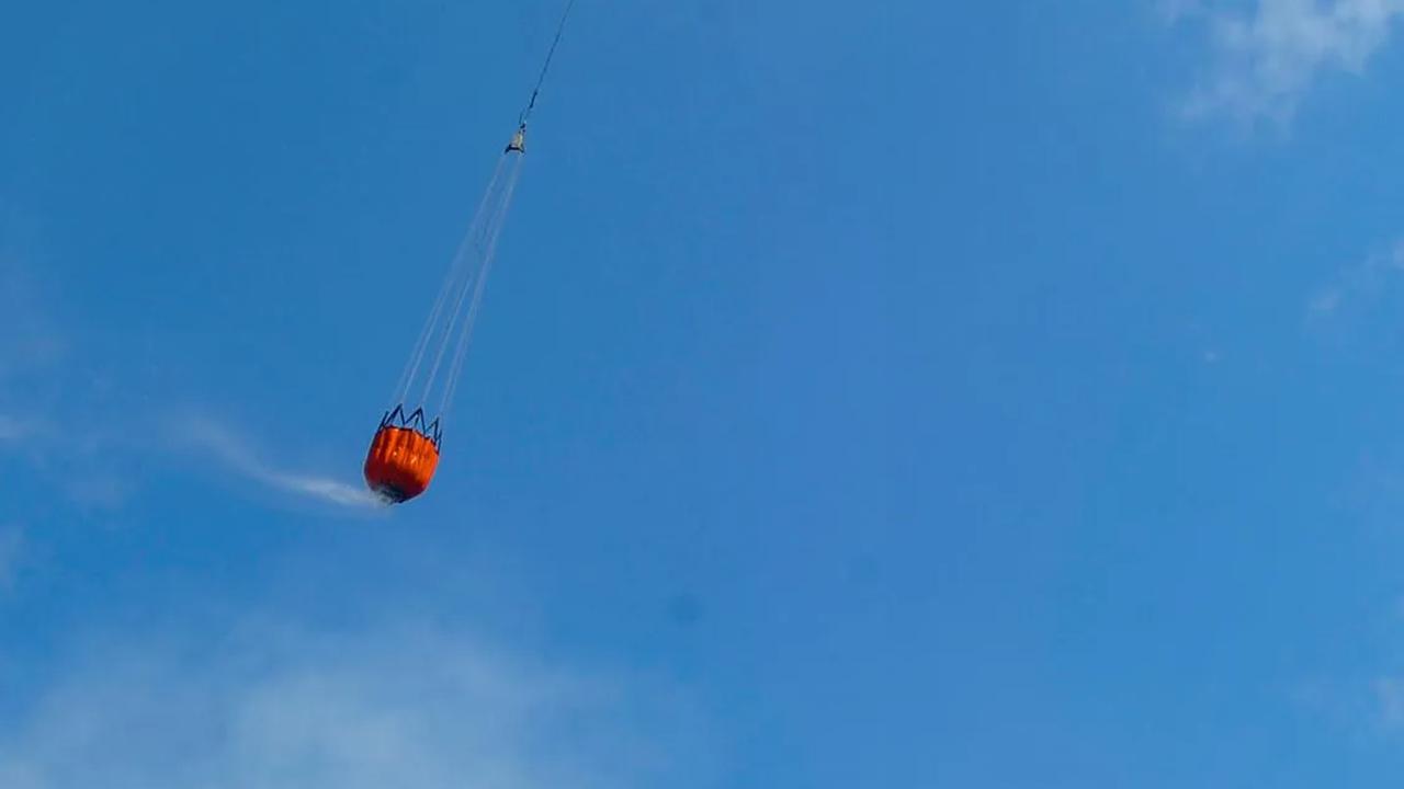 Helikopter water bombing BNPB menjatuhkan air saat melakukan pemadaman.
