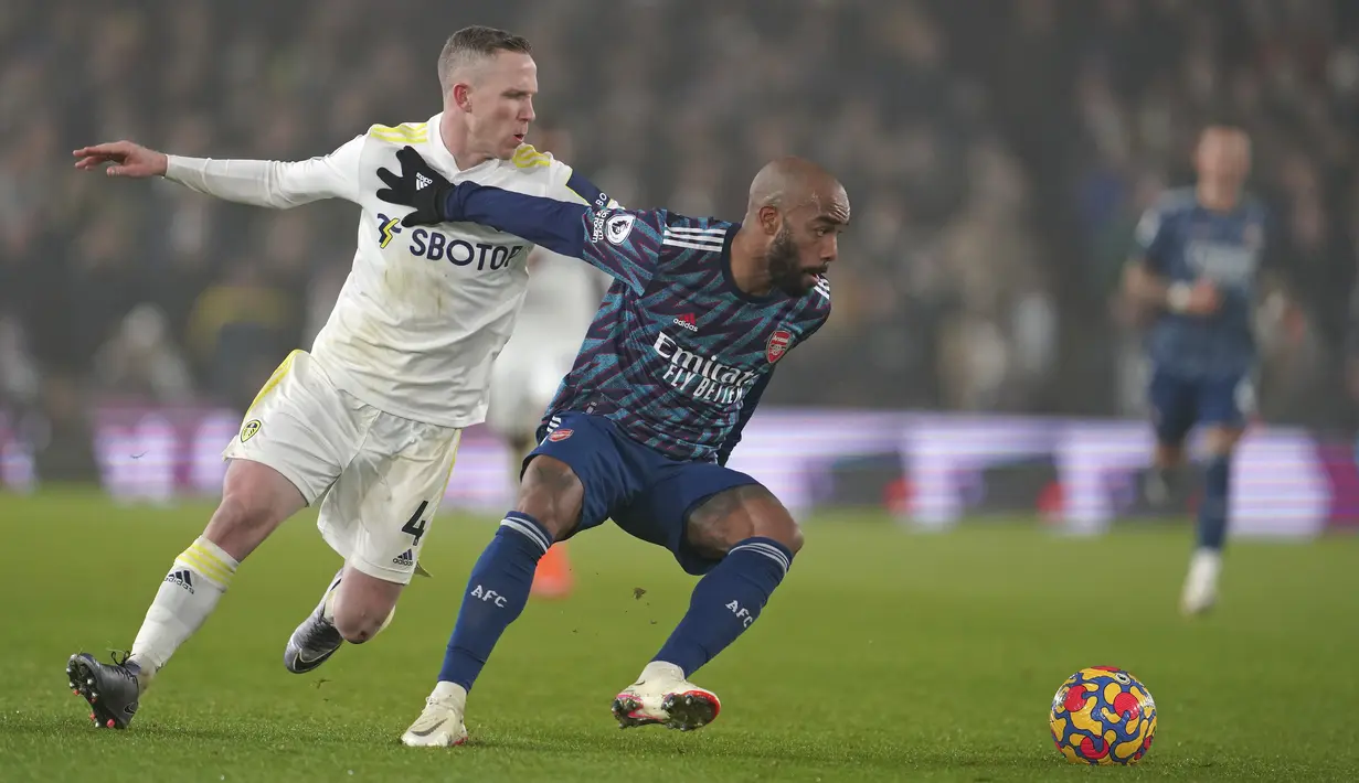 Gelandang Leeds United Adam Forshaw berebut bola dengan penyerang Arsenal Alexandre Lacazette pada pekan ke-18 Liga Inggris di Stadion Ellan Road, Leeds, Minggu (19/12/2021) dini hari WIB. Arsenal menang 4-1 di kandang Leeds United. (AP Photo/Jon Super)