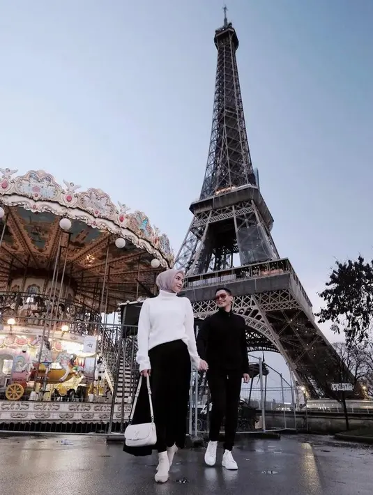 Pose di menara ikonik Eiffel, Ciki mengenakan turtleneck putih, long skirt hitam, dan boots krem.