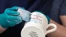 Seorang pekerja menyelesaikan pembuatan mug untuk merayakan pernikahan Pangeran Harry dan Meghan Markle di pabrik Emma Bridgewater di Stoke-on-Trent, Inggris (16/4). (AFP/Oli Scarff)