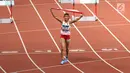 Pelari Indonesia, Nova Emilia membawa bendera merah putih usai finis di urutan kedua setelah pelari Korea Selatan Jung Hyelim pada final atletik nomor lari halang rintang 100 meter putri di Stadion Utama GBK, Jakarta (26/8). (Liputan6.com/Fery Pradolo)