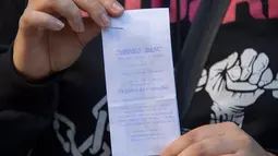 Seorang wanita menunjukkan bukti pendaftaran sebagai konsumen ganja di Montevideo, Urugay, Selasa (2/5). Mulai Juli, ganja bisa dengan mudah ditemukan di seluruh apotik di Uruguay yang dibanderol per gram sekitar Rp17 ribu. (Pablo PORCIUNCULA / AFP )
