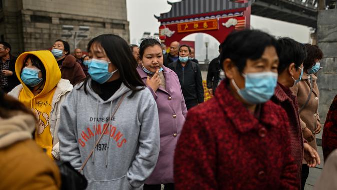 Turis domestik dari provinsi Henan yang mengenakan masker wajah mengunjungi daerah di sebelah Sungai Yangtze di Wuhan (20/11/2020). Dari total 50.340 kasus yang positif di Wuhan, 3.869 orang telah meninggal dunia akibat Covid-19 dan yang sembuh 46.471 orang. (AFP/Hector Retamal)