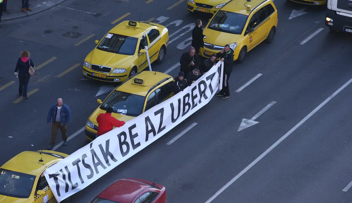 Sejumlah Sopir taksi membawa tulisan menolak layanan taksi online Uber di Budapest, Hongaria, (18/1). Tuntutan mereke berisi tentang resiko adanya aplikasi Uber terhadap pekerjaan mereka.  (AFP / Ferenc ISZA)