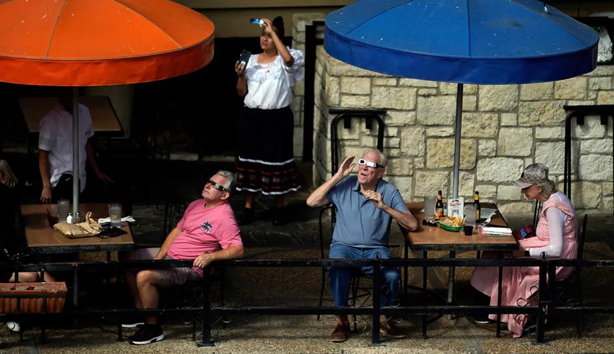 Pengunjung dan pekerja restoran di sepanjang Riverwalk menggunakan kacamata khusus untuk mengawasi pergerakan bulan di depan matahari saat terjadi Gerhana Matahari Cincin Api dari San Antonio, Texas, Amerika Serikat, Sabtu (14/10/2023). Sejumlah daerah tempat menyaksikan langsung Gerhana Matahari Cincin Api yakni Amerika Utara, Amerika Tengah, dan sebagian besar Amerika Selatan. (AP Photo/Eric Gay)
