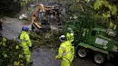 Pekerja membersihkan cabang pohon yang menghalangi Mirabel Avenue selama badai di Forestville, California, Minggu (24/10/2021). Badai kuat menerjang California Utara yang sempat mengalami kebakaran hutan, memicu tanah longsor dan banjir, juga membawa angin kencang. (AP Photo/Ethan Swope)