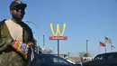 Seorang pria berjalan dengan latar belakang plang logo restoran McDonald's yang terbalik di Lynwood, California (8/3). Logo tersebut dibalik dari huruf M menjadi huruf W untuk peringati Hari Perempuan Internasional. (AFP Photo/Frederic J. Brown)
