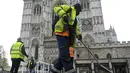 Orang-orang bekerja saat menyiapkan lahan di depan Westminster Abbey pada hari upacara penobatan Raja Charles III  di London, Sabtu (6/5/2023). (Toby Melville/Pool Photo via AP)