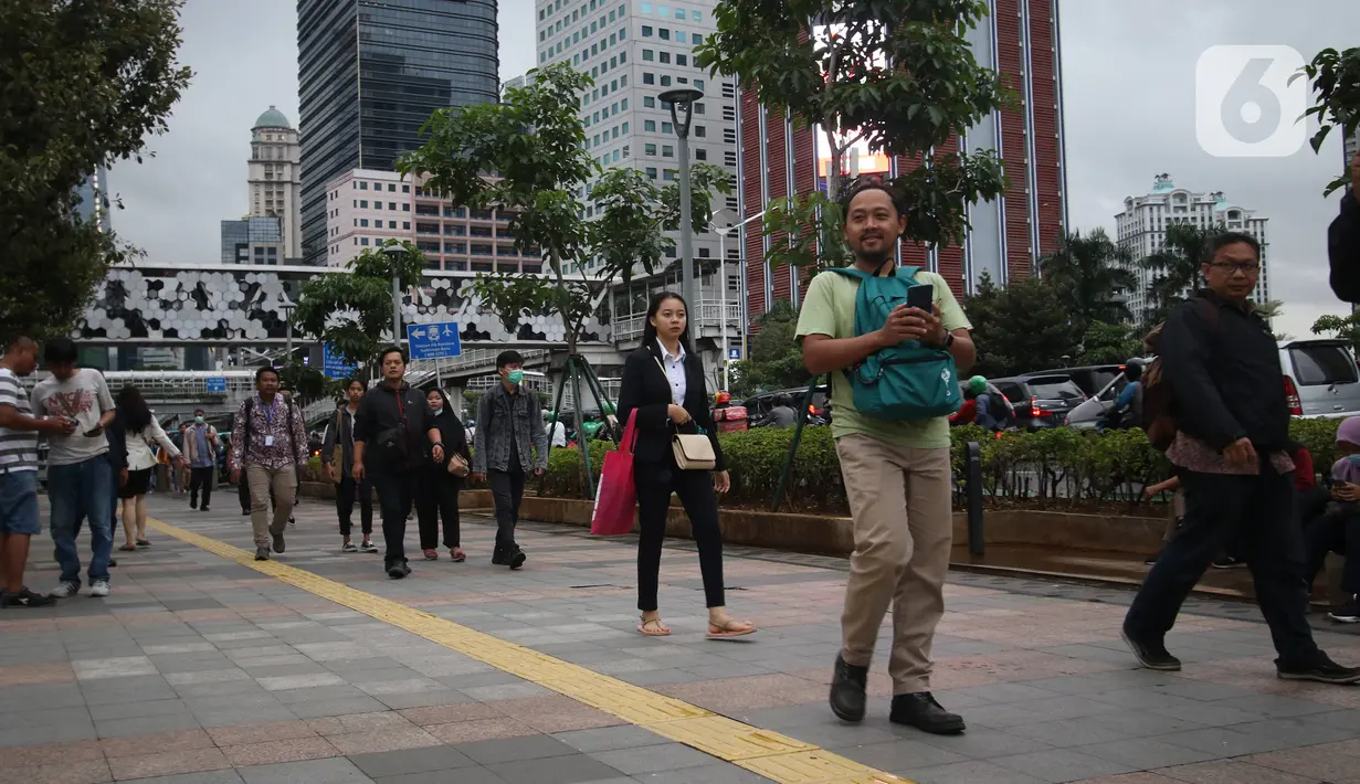Pekerja berjalan kaki saat jam pulang di kawasan Sudirman, Jakarta, Jumat (7/2/2020). BPJS Ketenagakerjaan yang kini bernama BP Jamsostek menargetkan sekitar 23,5 juta tenaga kerja baru masuk dalam daftar kepesertaan pada 2020. (Liputan6.com/Angga Yuniar)