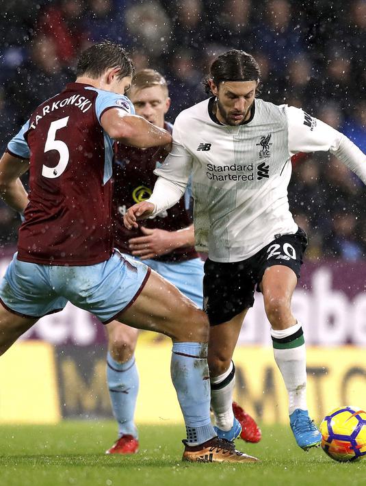 Pemain Burnley, James Tarkowski (kiri) menghalau bola dari kaki pemain Liverpool, Adam Lallana pada lanjutan Premier League di Turf Moor, Burnley, (1/1/2018). Liverpool menang 2-1 atas Burnley. (Martin Rickett/PA via AP)