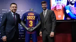 Bek Spanyol, Gerard Pique dan Presiden Barcelona FC, Josep Maria  berpose dengan jersey Barcelona pada pengumuman perpanjangan kontraknya di stadion Camp Nou, Senin (29/1). Pique memperpanjang kontraknya bersama Barcelona hingga 2022. (LLUIS GENE/AFP)
