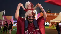 Pendukung Timnas Qatar berpose di depan fotografer saat menunggu pembukaan Piala Dunia 2022 di Hayya Fan Zone, Lusail pada Minggu (20/11/2022). (AP/Lee Jin-man)