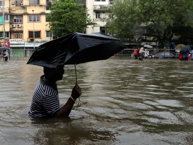 Seorang pria menggunakan payung sambil berjalan melewati banjir yang merendam kota Mumbai, India, Selasa (29/8). Hujan lebat yang terus-menerus mengguyur Mumbai mengakibatkan banjir di beberapa daerah di kota tersebut. (AP Photo/Rajanish Kakade)