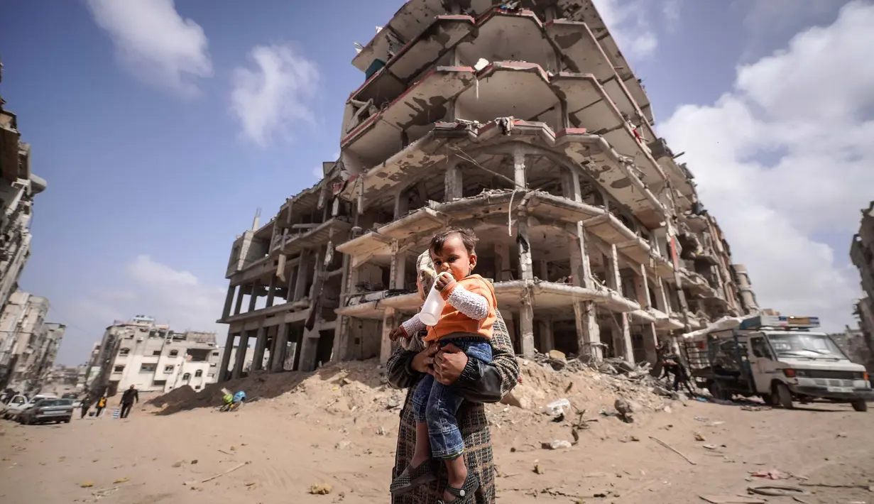 <p>Seorang wanita Palestina bersama seorang anak berdiri di depan puing-puing rumah yang hancur akibat pengeboman Israel di Khan Yunis di Jalur Gaza selatan pada 6 Maret 2024. (Foto oleh AFP)</p>