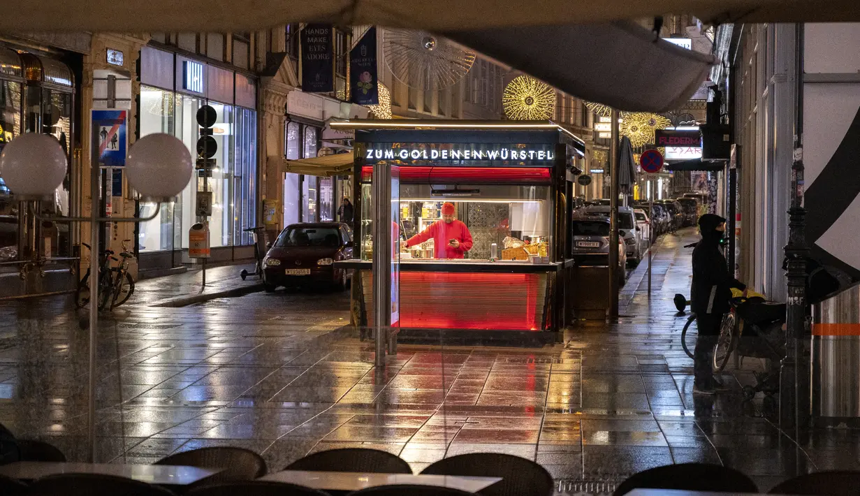 Seorang penjual hotdog menunggu pelanggan di Graben, sebuah jalan di pusat kota Wina yang biasanya penuh sesak dengan kerumunan orang pada Senin (22/11/2021). Austria kembali menerapkan lockdown penuh untuk mengekang infeksi Covid-19 menyebar ke seluruh Eropa. (JOE KLAMAR / AFP)