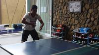 Bek Bali United, Abdulrahman bermain tenis meja. Peralatan tenis meja berada di dalam mes sehingga saat senggang pemain bisa langsung beradu pingpong. (Bola.com/Permana Kusumadijaya)