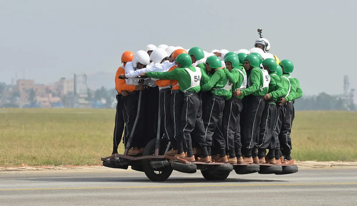 Anggota Tornado dari Army Service Corps (ASC) berada di satu motor 500 cc di Bangalore, India (19/11). Tim Tornado menciptakan rekor dunia baru setelah 58 orang naik satu motor 500 cc dan mengendarainya sejauh 1200 meter. (AFP Photo/Manjunath Kiran)