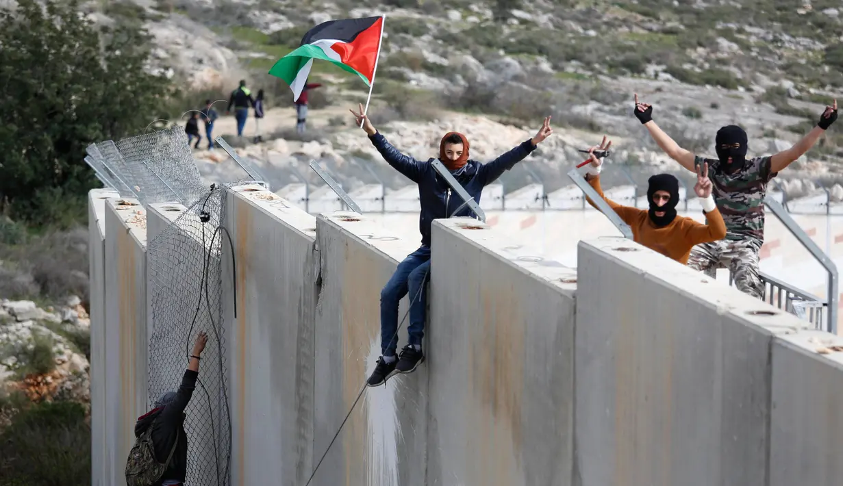 Pengunjuk rasa Palestina memanjat tembok pemisah dengan Israel saat aksi di desa Tepi Barat Bilin dekat Ramallah, Jumat (17/2). Aksi tersebut untuk memperingati 12 tahun protes mereka atas tembok pemisah tersebut. (AP Photo / Majdi Mohammed)