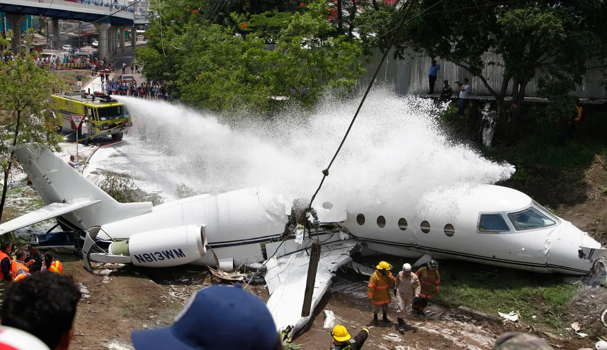 Mobil pemadam kebakaran menyemprotkan busa ke pesawat jet pribadi Gulfstream G200yang tergelincir dari landasaan saat mendarat di Bandara Tegucigalpa, Honduras, Selasa (22/5). Sedikitnya 6 dilaporkan terluka dalam insiden tersebut. (AP/Fernando Antonio)