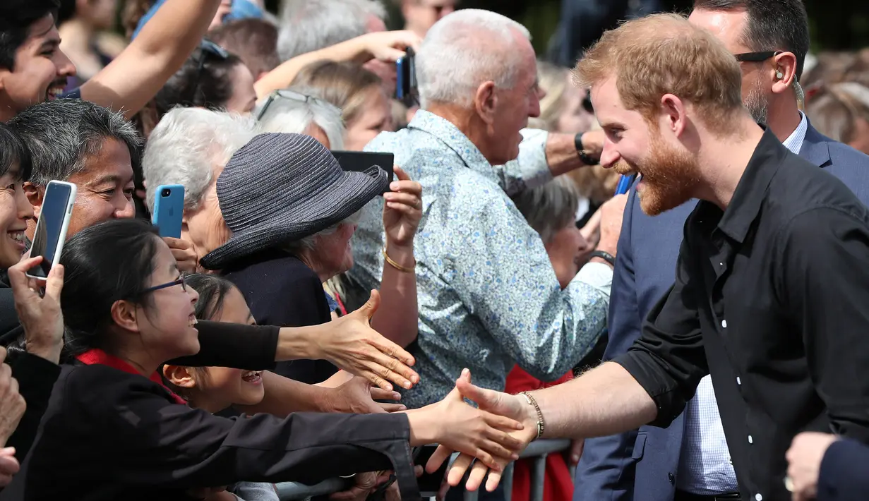 Pangeran Harry tertawa saat menyalami anak kecil di Taman Pemerintah Rotorua, Selandia Baru, Rabu (31/10). Pangeran Harry dan Meghan Markle sedang dalam tur tiga minggu di Australia, Selandia Baru, Tonga, dan Fiji. (Michael Bradley/Pool/AFP)