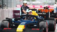 Pembalap Red Bull Racing, Max Verstappen (kanan) dan Yuki Tsunoda melakukan parede mobil lego sebelum balapan Formula 1 GP Miami 2025 yang berlangsung di Sirkuit Autodromo, Miami, Florida, Minggu (04/05/2025) waktu setempat. (AFP/Mark Thompson)