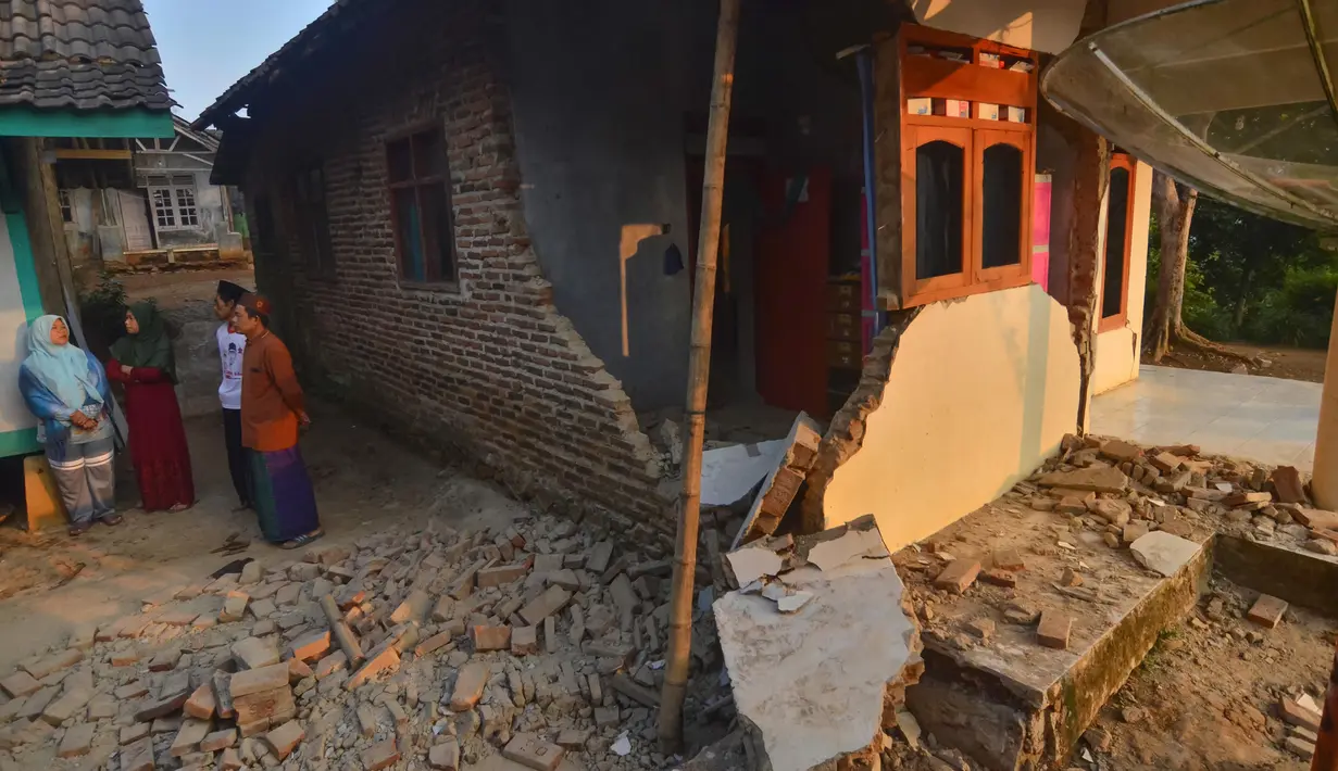 Warga berbincang dekat rumah yang rusak usai gempa melanda Pandeglang, Banten, Sabtu (3/8/2019). Sekitar 500 warga Kecamatan Sumur, Ujung Kulon, Kabupaten Pandeglang, masih mengungsi di Hunain Sementara (Huntara) akibat gempa Banten. (RONALD SIAGIAN/AFP)