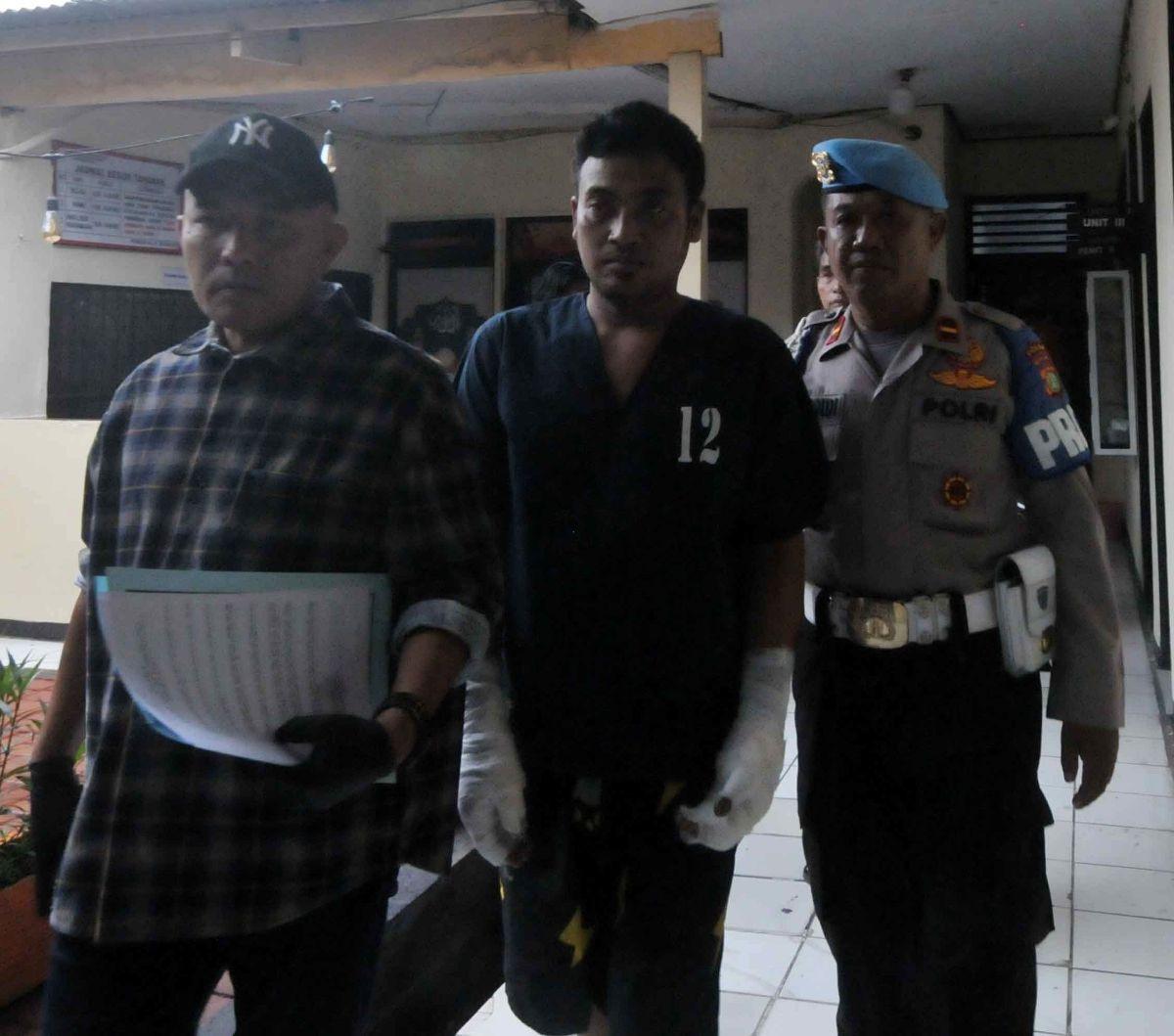 Tersangka EST (34) digelandang petugas untuk dihadirkan dalam rilis kasus penganiayaan di Mapolsek Pasar Rebo, Jakarta Timur, Selasa (25/6/2024). EST, joki permainan tong setan, ditangkap setelah membakar hidup-hidup rekannya, AMG (31), yang merupakan tuy