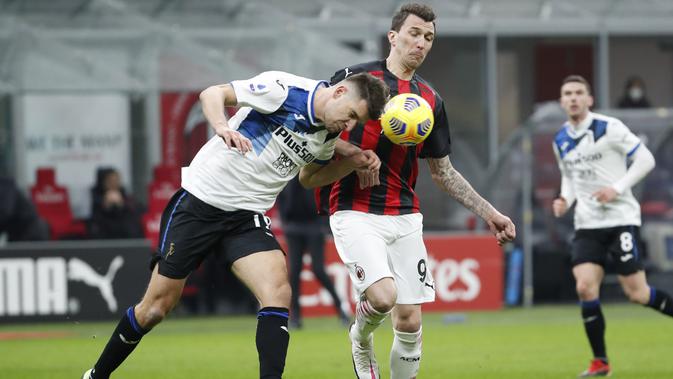 Penyerang AC Milan, Mario Mandzukic berebut bola dengan bek Atalanta, Berat Djimsiti pada pertandingan lanjutan Liga Serie A Italia di Stadion San Siro, Minggu (24/1/2021). Meski kalah, hasil Liga Italia ini tetap membuat AC Milan berada di puncak klasemen. (AP Photo/Antonio Calanni)