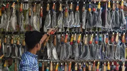 Seorang pria memilih pisau yang dipasangkan rantai untuk ritual pencambukan diri selama ritual berkabung Ashura di sebuah toko di Lahore, Pakistan (18/9). Umat Syiah Pakistan akan memperingati hari Ashura pada 21 September. (AFP Photo/Arif Ali)