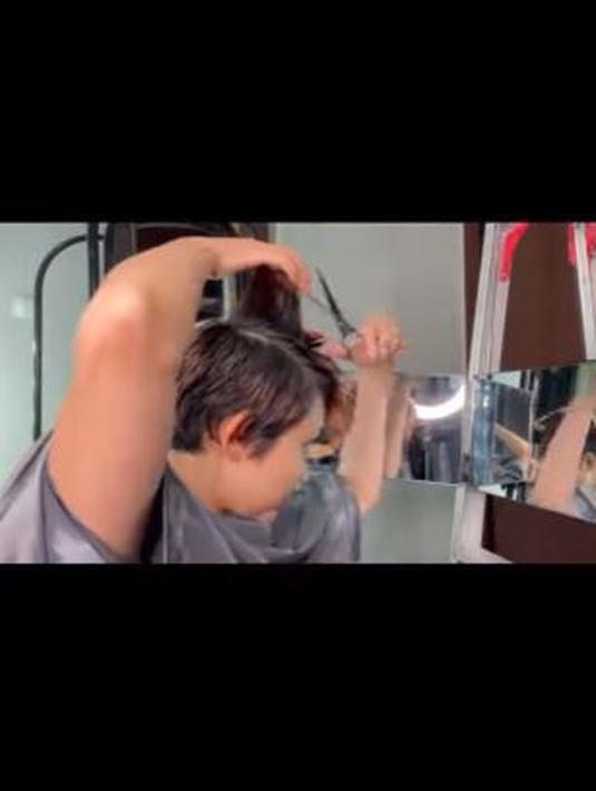 Rina Nose, tampak asyik memotong rambutnya hingga pendek. Ia hanya mengandalkan kaca dan gunting saja. (Foto: Instagram/@rinanose16)