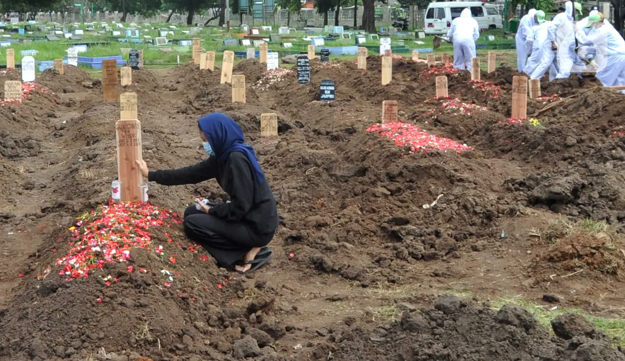 Seorang perempuan berdoa di salah satu makam khusus Covid-19 di TPU Tegal Alur, Jakarta, Kamis (17/12/2020). Hingga hari ini, intensitas pemakamanan korban covid-19 di DKI masih tinggi dengan rata-rata yang dimakamkan mencapai 30 hingga 38 jenazah per hari. (merdeka.com/Arie basuki)
