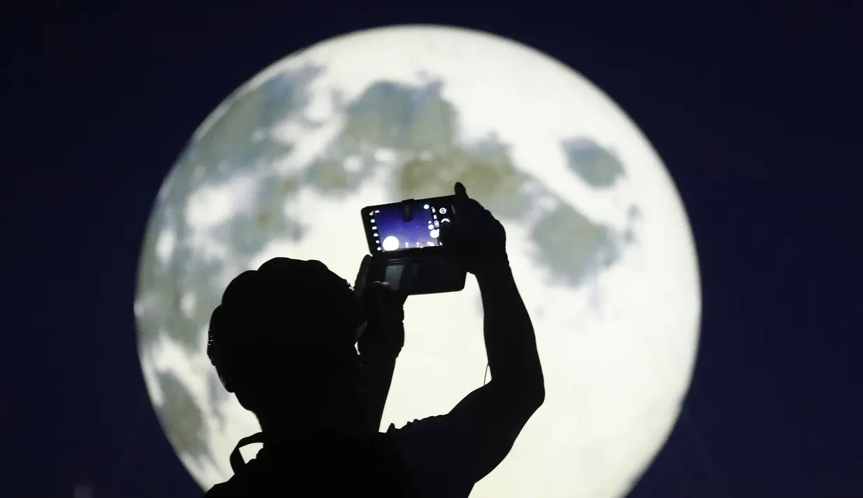 Warga memotret instalasi bulan purnama yang bersinar di sebuah taman di Seoul, Korea Selatan, Jumat (18/9/2020). Pejabat setempat memasang bulan purnama buatan untuk meningkatkan semangat saat wabah COVID-19 sekaligus menyambut Chuseok, Thanksgiving versi Korea. (AP Photo/Ahn Young-joon)