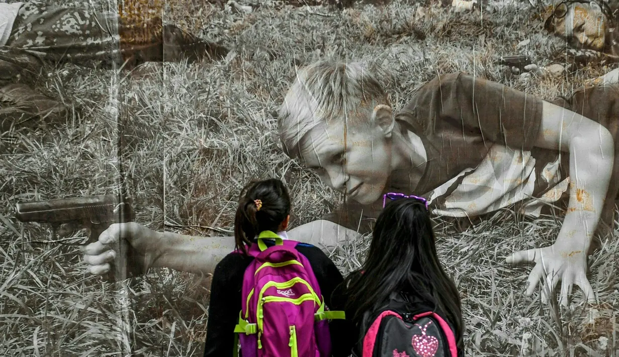 Dua anak sekolah melihat foto jurnalistik karya Sara Blesener, Kolombia (1/11). Karya ini diprakarsai oleh Dysturb, sebuah komunitas jurnalis foto yang berkeinginan membuat informasi visual secara bebas diakses oleh khalayak luas. (AFP PHOTO/luis acosta)