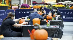 Warga New York mengukir labu dalam persiapan untuk Halloween di Rockefeller Center (22/10/2020). Kelas mengukir labu adalah bagian dari ZO Tishman Speyer. program fasilitas untuk semua orang yang bekerja di gedungnya. (Diane Bondareff/AP Images for Tishman Speyer)