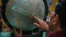Seorang wisatawan memperhatikan bola peta dunia di Tugu Khatulistiwa, Pontianak, Kalimantan Barat, 23 Agustus 2015. Ikon wisata kota Pontianak ini masih menjadi primadona wisata sejarah bagi wisatawan lokal maupun luar. (Liputan6.com/Faizal Fanani)