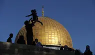 Siluet jamaah Muslim saat merayakan di depan masjid Dome of the Rock sebelum sholat Idul Fitri pagi, yang menandai akhir bulan suci Ramadhan, di kompleks masjid Al-Aqsa, di Yerusalem (13/5/2021). (AFP/Ahmad Gharabli)