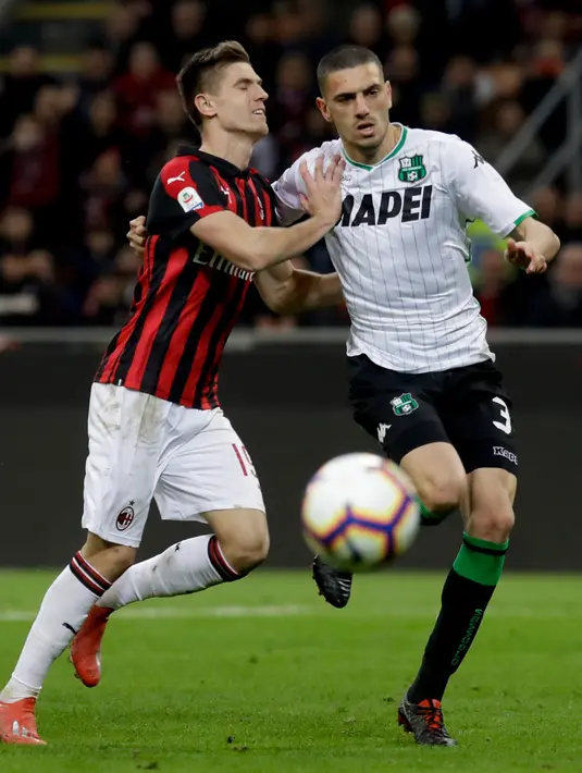 Striker AC Milan, Krzysztof Piatek berebut bola dengan bek Sassuolo, Merih Demiral selama pertandingan lanjutan Liga Italia di stadion San Siro (2/3). Kemenangan ini mengantar Milan masuk tiga besar klasemen melangkahi Inter Milan. (AP Photo/Luca Bruno)