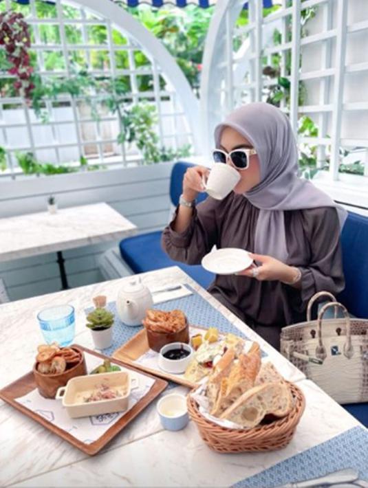 Selain berpose di pinggir jalan, Syahrini juga sempat menikmati momen tersebut di sebuah restoran. Begini gayanya saat minum teh hangat ditemani roti, masih menenteng tas Birkin Hermes-nya. (instagram.com/princessyahrini)
