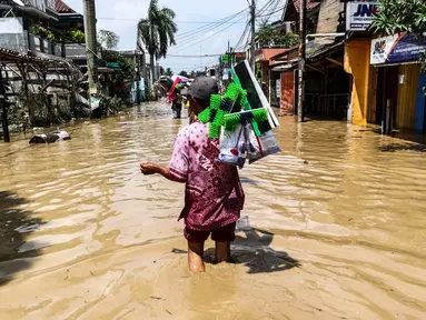 Pedagang alat kebersihan menerobos banjir di kompleks Pondok Gede Permai, Jatiasih, Bekasi, Jumat (22/4). Mereka menjajakan dagangannya berupa alat kebersihan ketika banjir di  kawasan tersebut mulai surut. (Liputan6.com/Fery Pradolo)