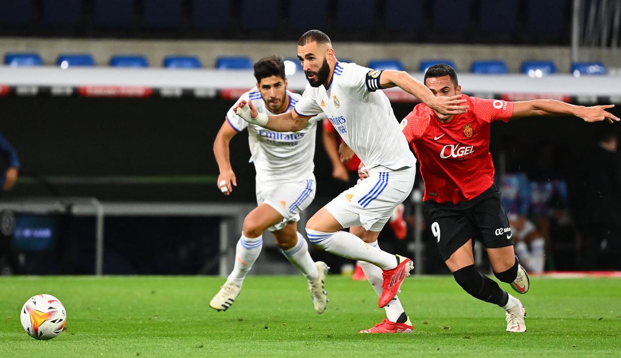 Karim Benzema (tengah) menjadi keran gol Real Madrid saat laga baru berjalan tiga menit. Benzema mampu memanfaatkan kesalahan pemain belakang Mallorca, Josep Gaya dan sukses menaklukkna kiper Manolo Reina. (AFP/Gabriel Bouys)